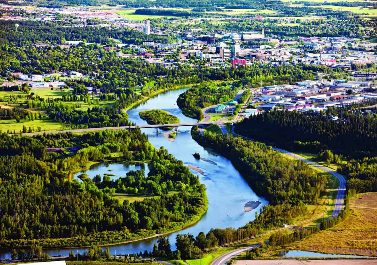 Aerial view of the Red Deer River winding through Red Deer County with bridges, forests, city and industrial areas.