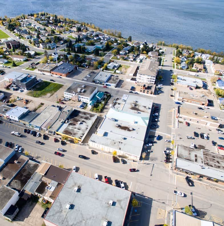 Aerial view of Lac La Biche town center with shops, parking lots, and the lake shore in the background.