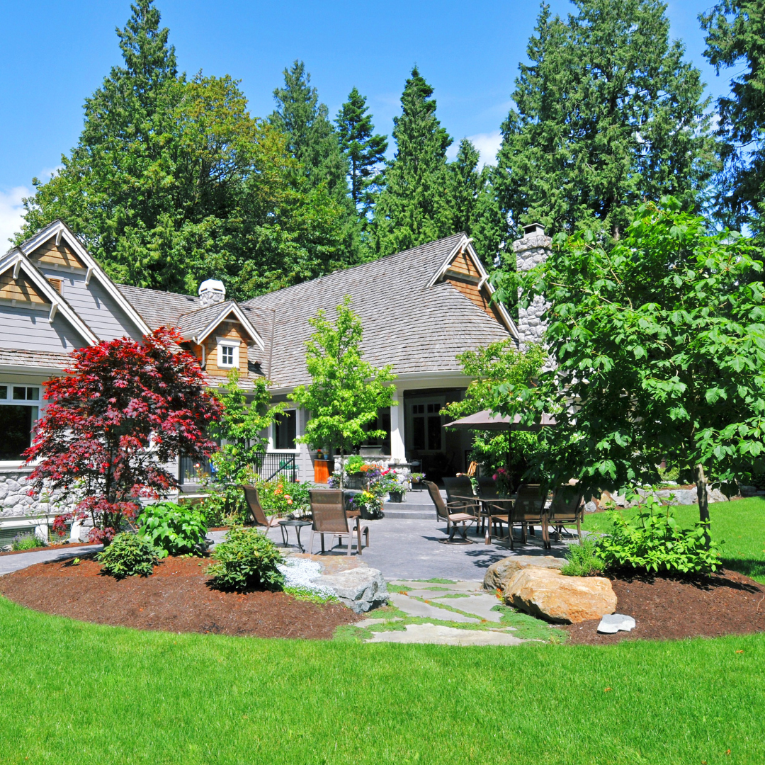 Landscapedyard with green lawn, colorful trees, stone path, and patio seating