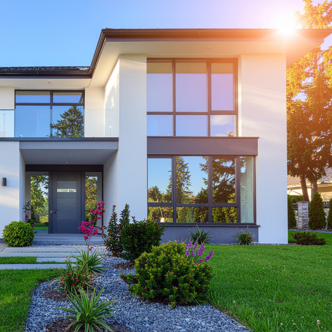 Image of a modern house with neatly trimmed lawn and floral landscaping in front of sun