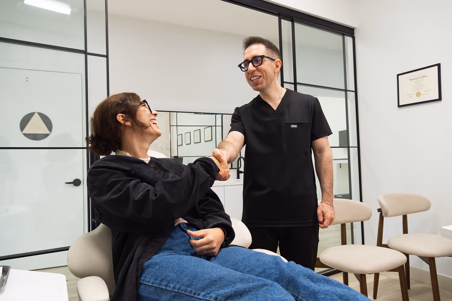 A man shaking hands with a woman in a chair.
