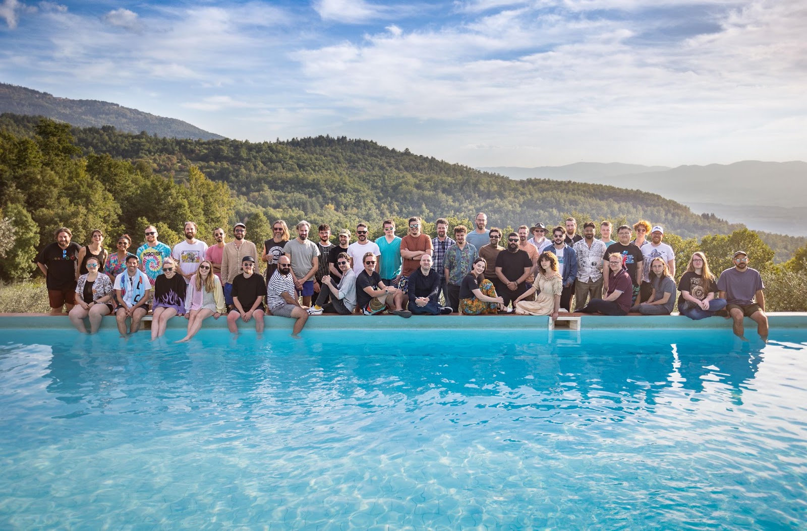 The whole studio posing by the pool with the beautiful Tuscan mountains in the background