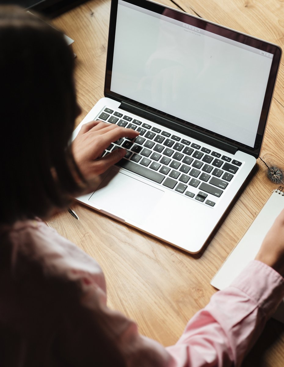 Young professional taking notes while working on a laptop, representing early career workforce development and credential strategy research.