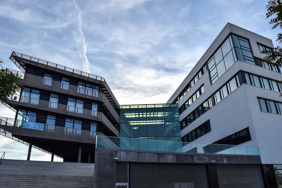 A modern glass-facade building against a blue sky, featuring innovative architecture.