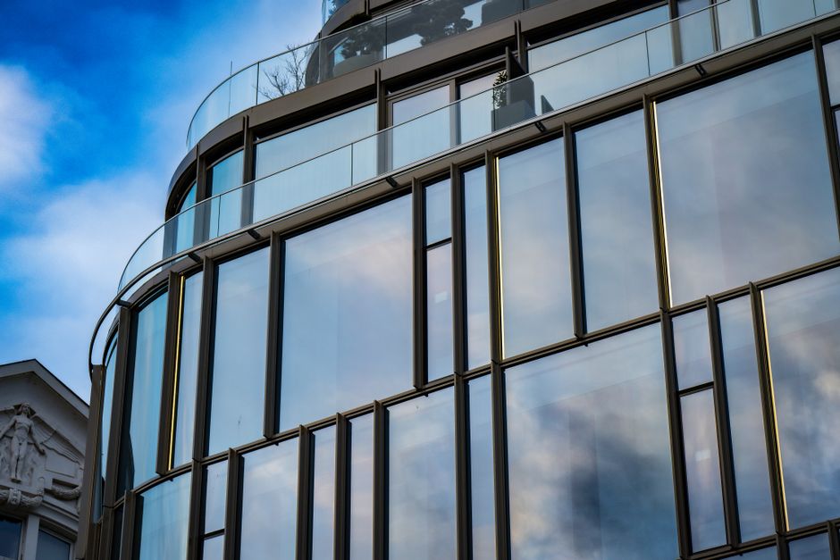 Contemporary glass building facade reflecting blue sky and clouds in Budapest, Hungary.