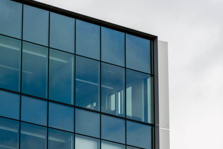 Close-up view of a modern building facade featuring blue glass windows against a cloudy sky.