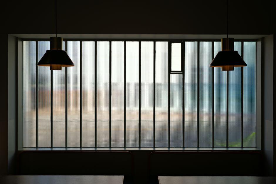 Modern indoor setting with pendant lights and a ribbed glass window providing ambient lighting.