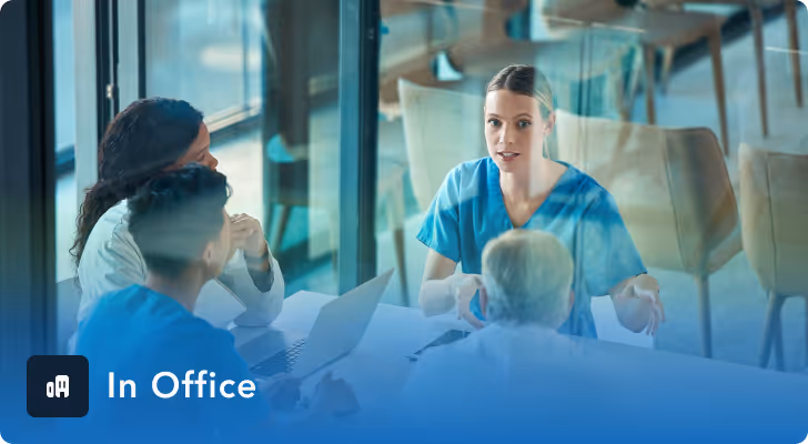 Four medical professionals in discussion around a table in a modern office setting.