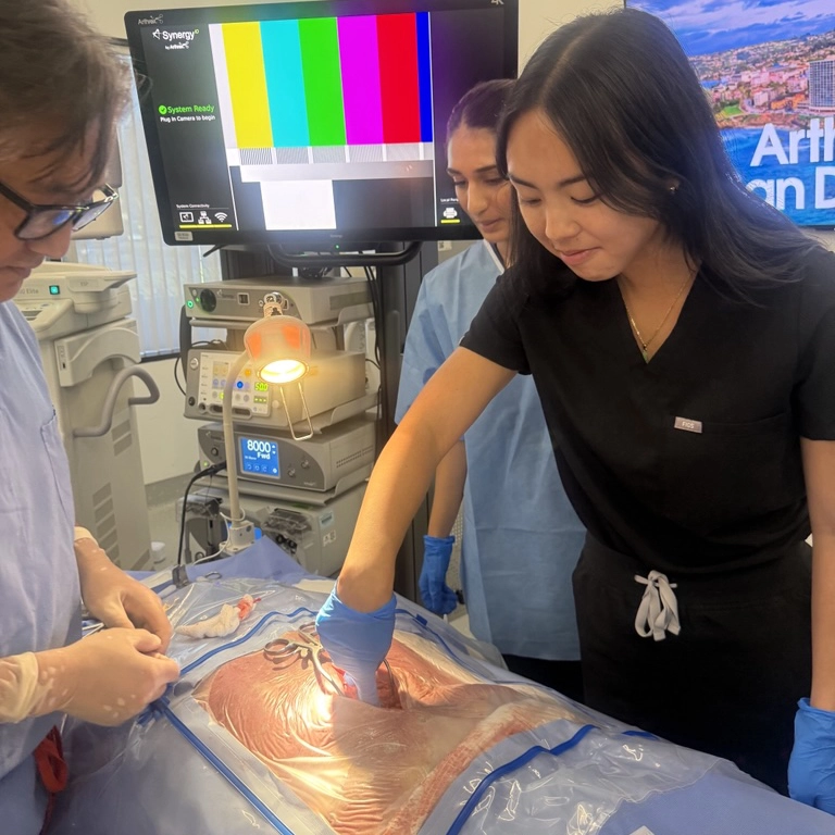 Three medical professionals practicing a procedure on a simulation mannequin in a clinical setting.