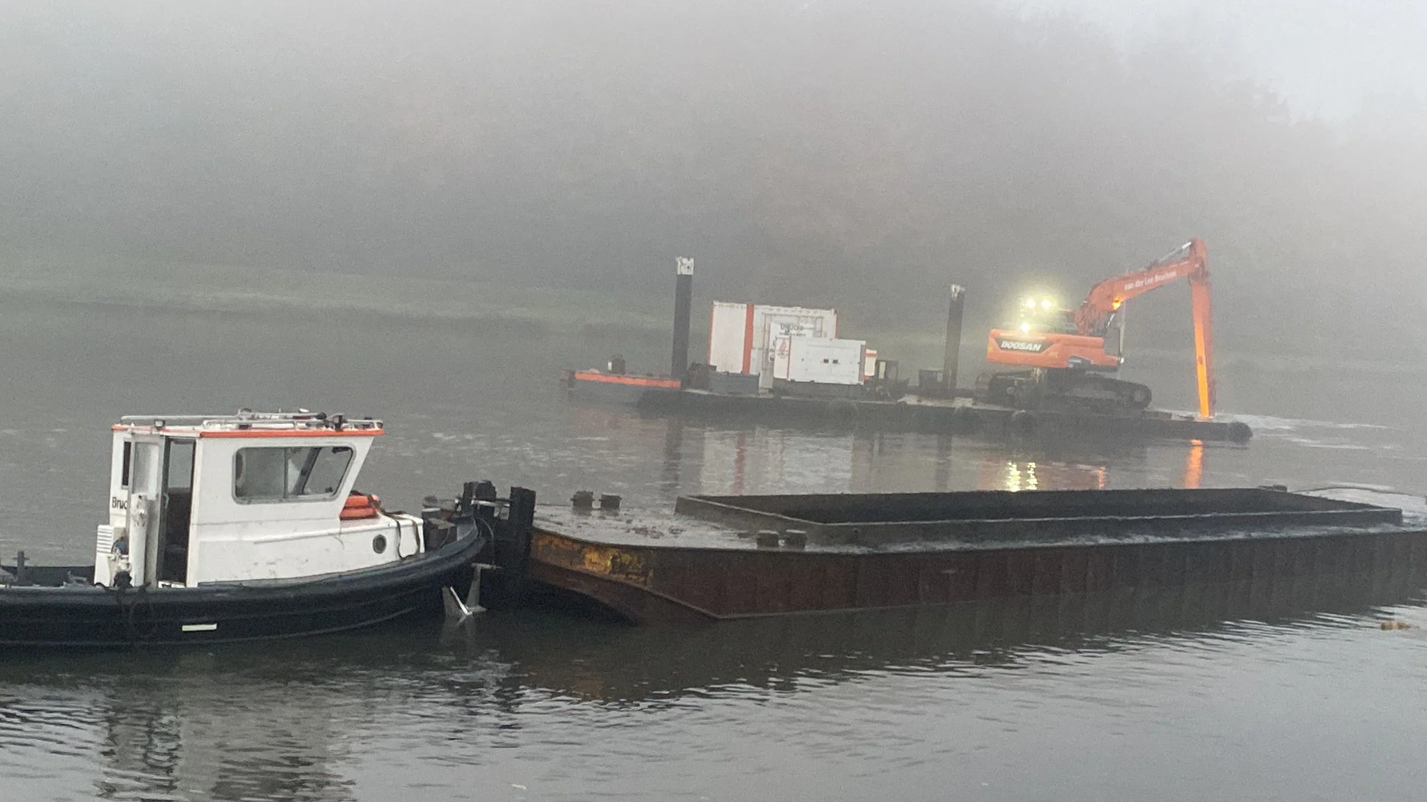 Vroege ochtendmist boven de Bosbaan in Amsterdam, met een ponton waarop een graafmachine van Van der Lee Bruchem baggerwerk uitvoert.