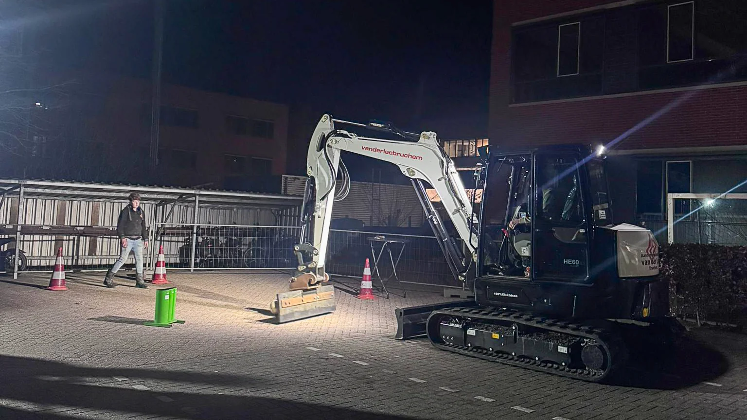 Bezoekers bekijken een mini graafmachine van Van der Lee Bruchem tijdens een avondactiviteit op een verlicht terrein