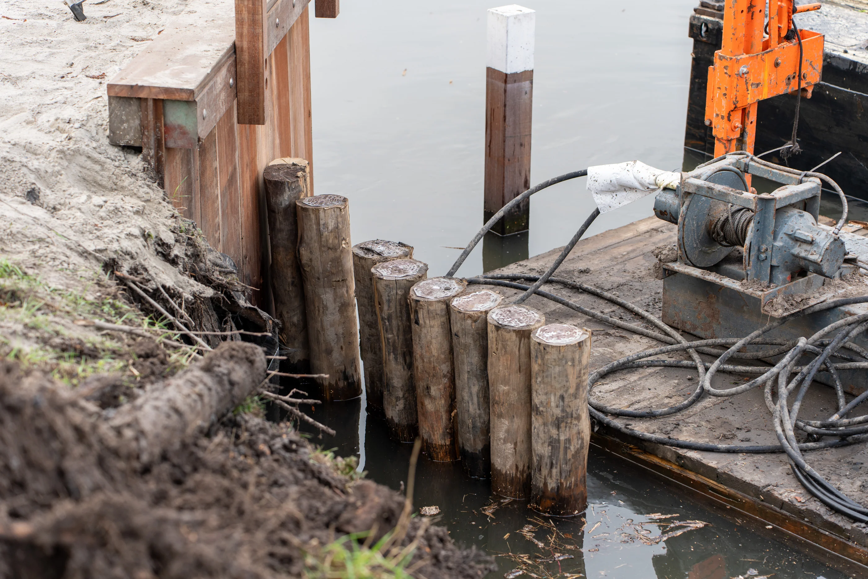 Detail van houten palen en lierinstallatie op ponton bij aanleg van beschoeiing