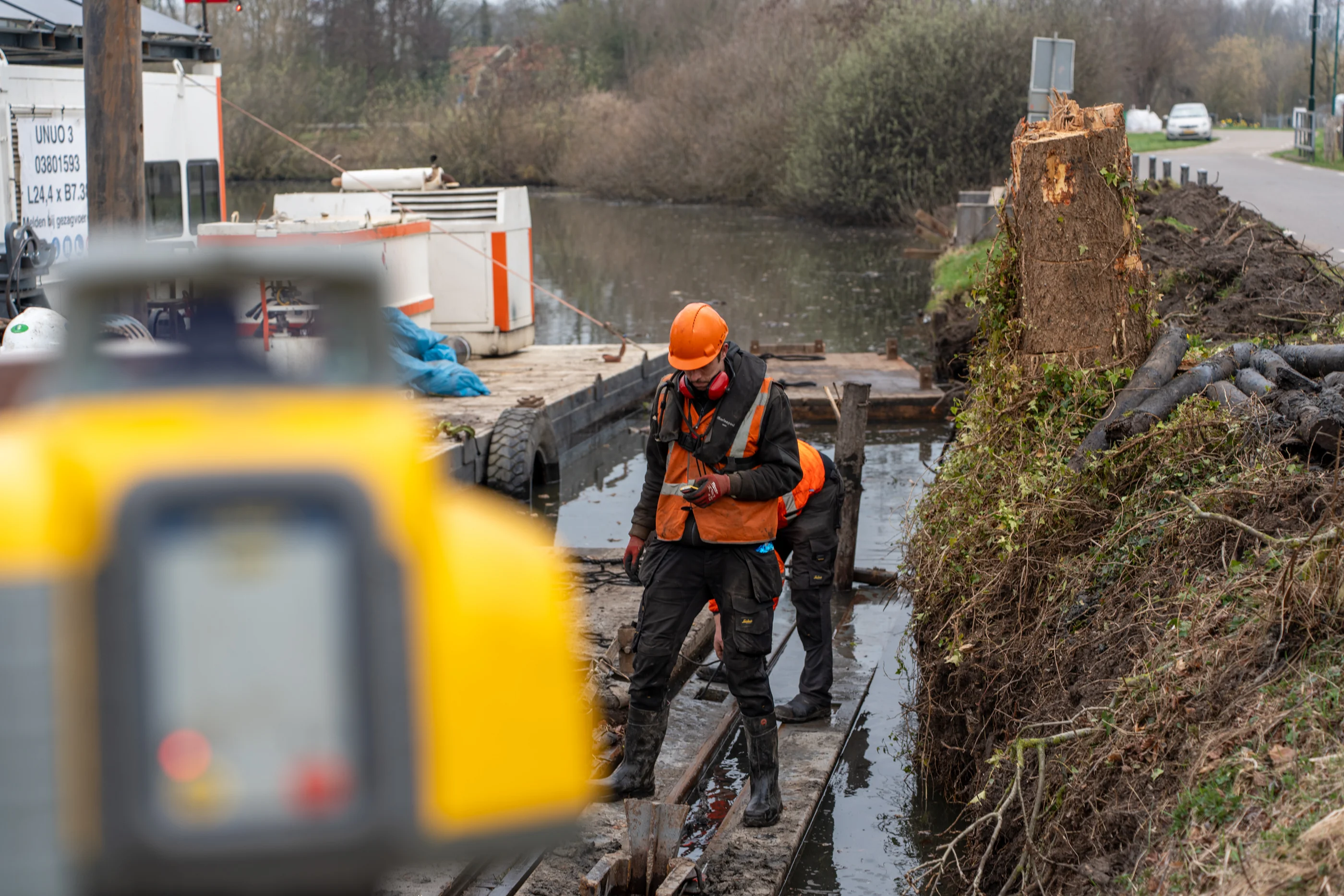 Medewerkers aan het werk op ponton tijdens oeverwerkzaamheden langs een watergang