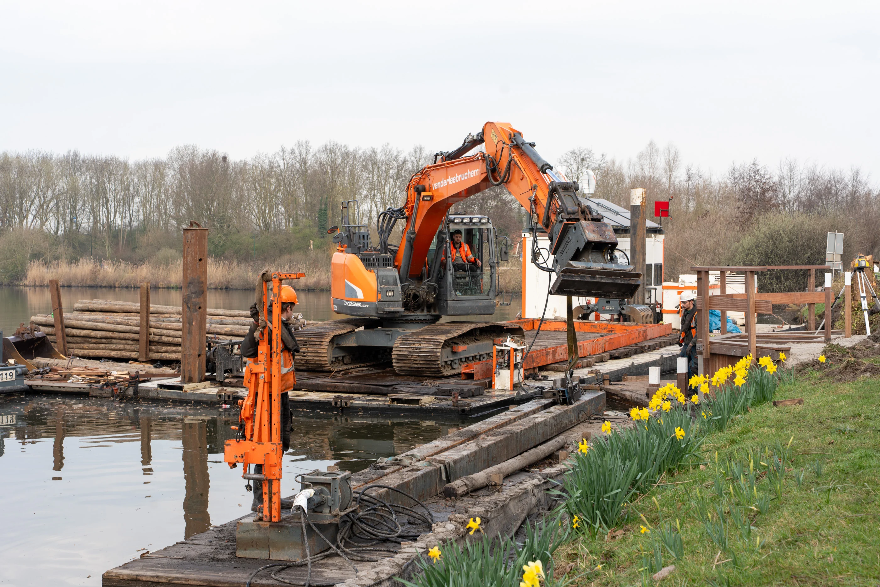 Graafmachine op ponton tijdens werkzaamheden aan een oever langs het water