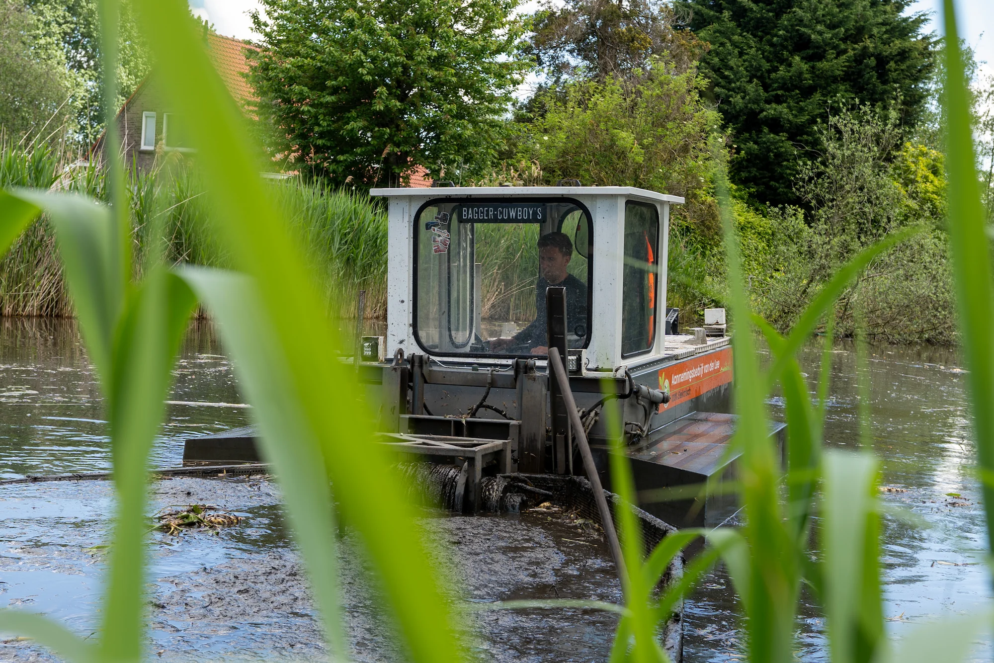 elektrische schuifboot van aannemingsbedrijf van der lee Bruchem in actie op een watergang. 
