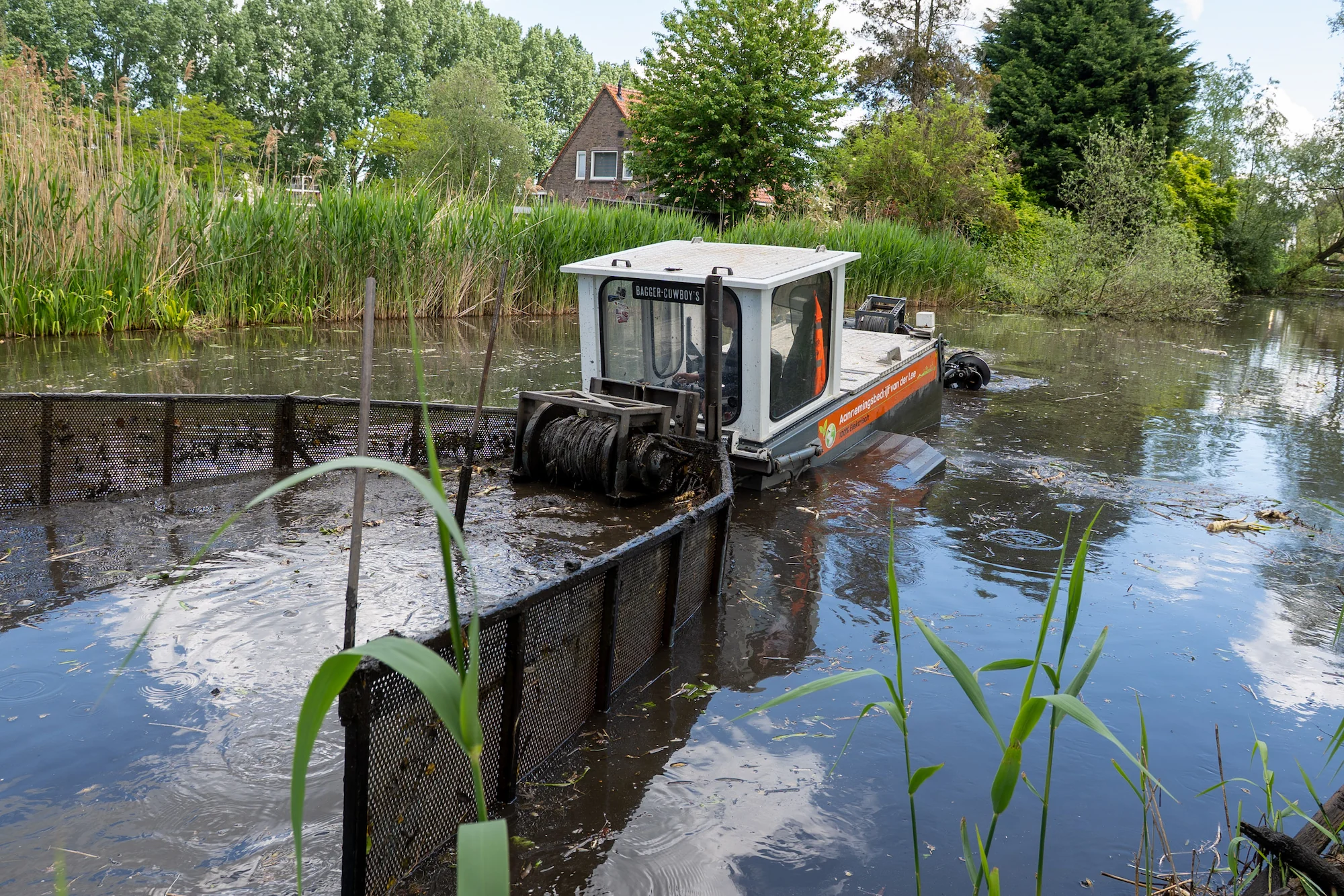 Elektrische schuifboot verzamelt bagger uit de watergang voor transport naar het overslagpunt.