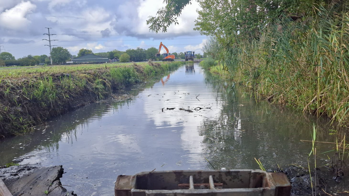 Watergang tijdens baggerwerkzaamheden, met een rupskraan van Van der Lee Bruchem op de achtergrond.