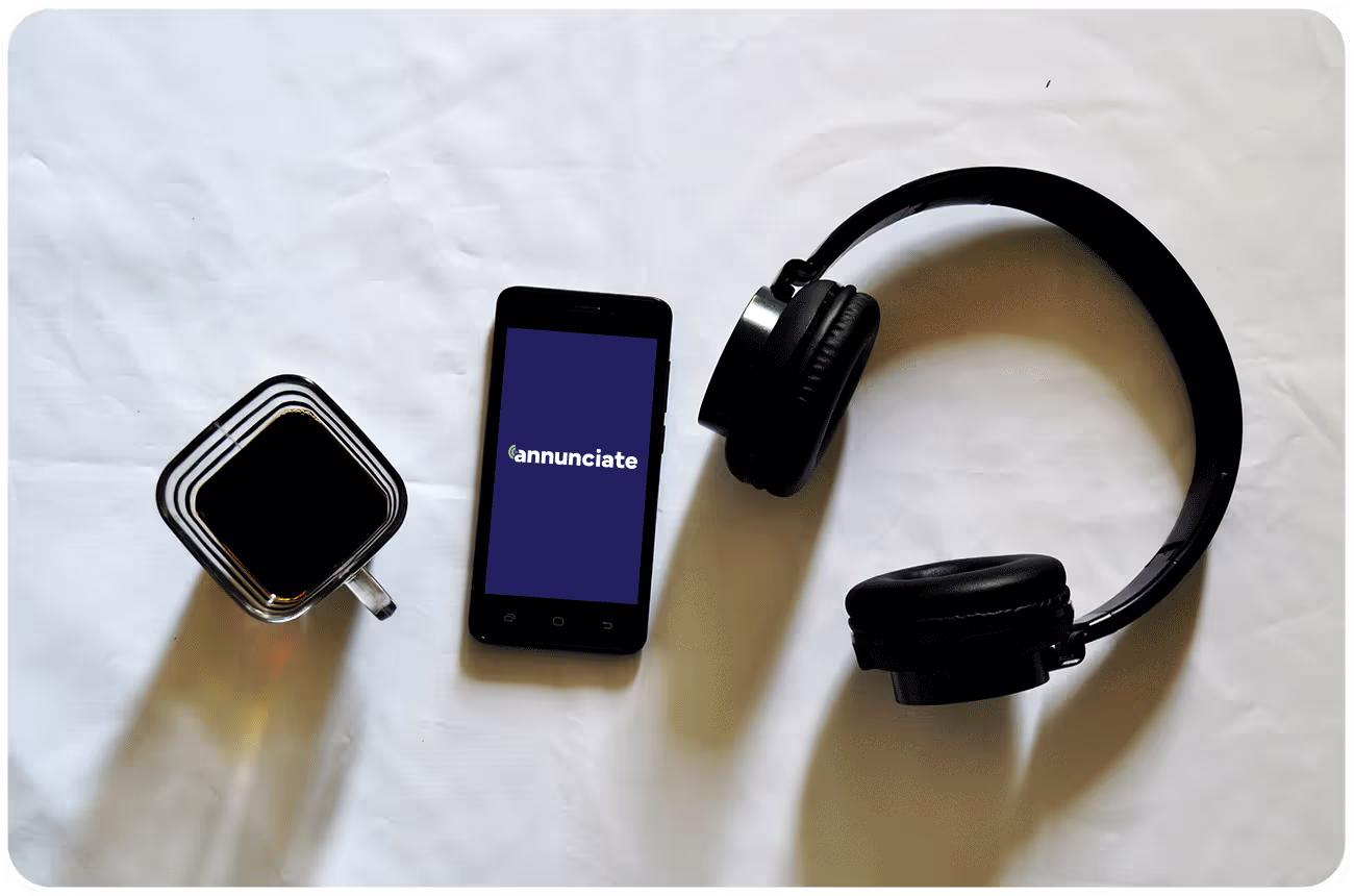 Mobile phone with the Annunciate app and black headphones on a white background