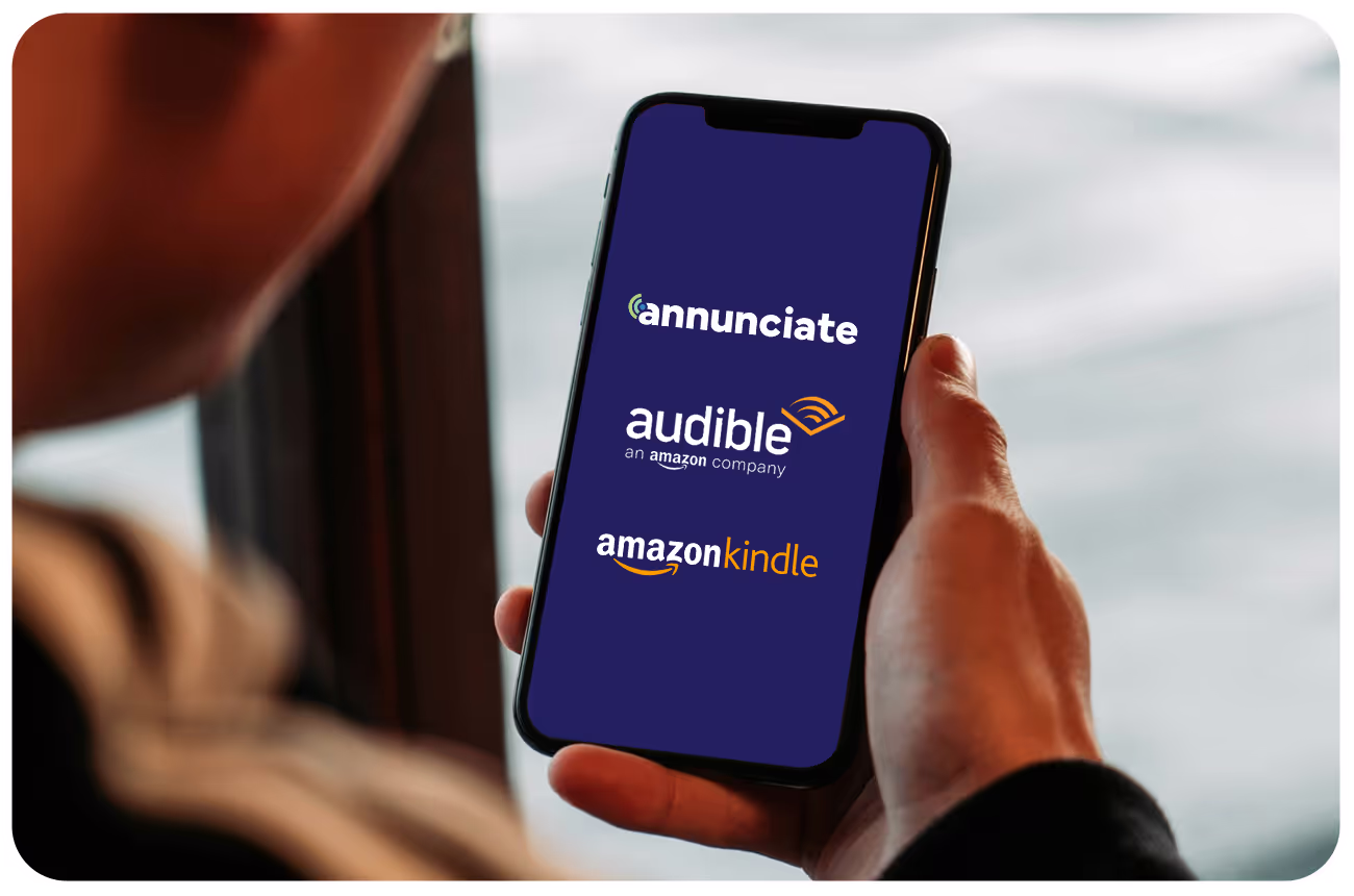 Close-up of a man looking at his phone with the Annunciate, Audible, and Amazon Kindle logos