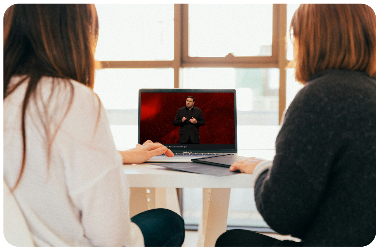 Two women sitting in front of a laptop watching a video