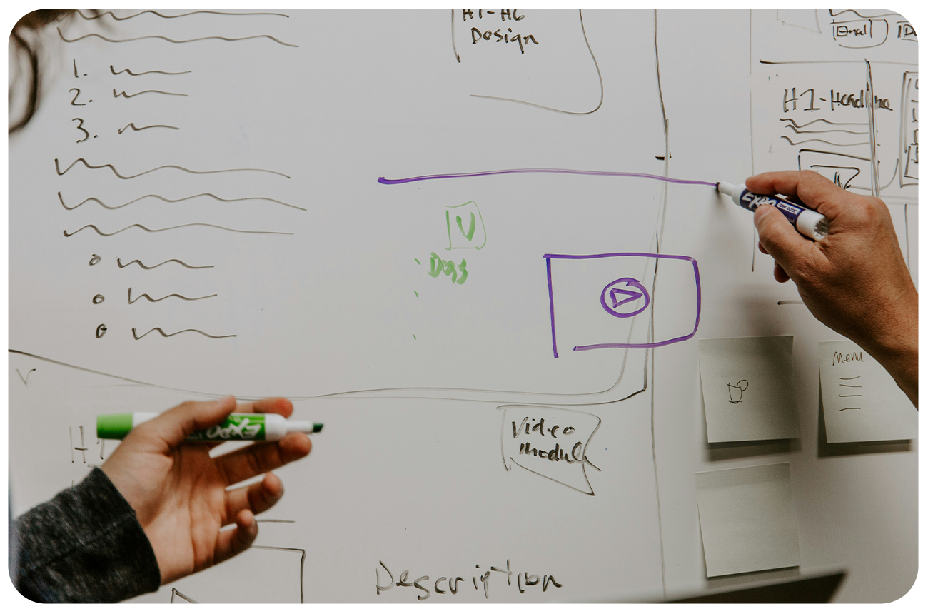 Closeup of two coworkers sketching plans on a whiteboard