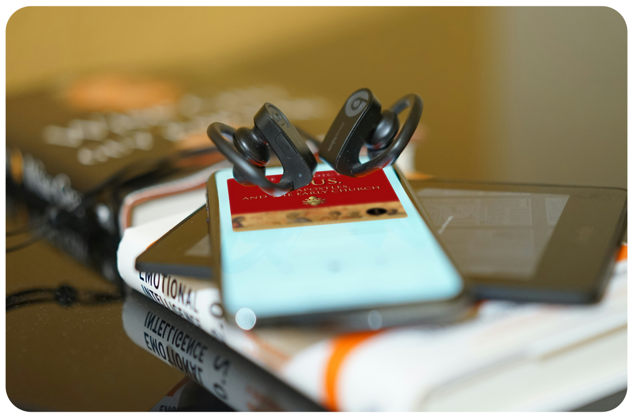 Hardcover book with a smartphone and earbuds playing an audiobook