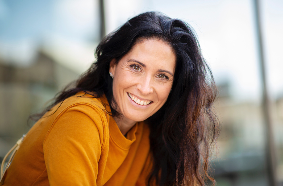 A beautiful woman smiles with healthy, white teeth after a full mouth reconstruction in Campbell