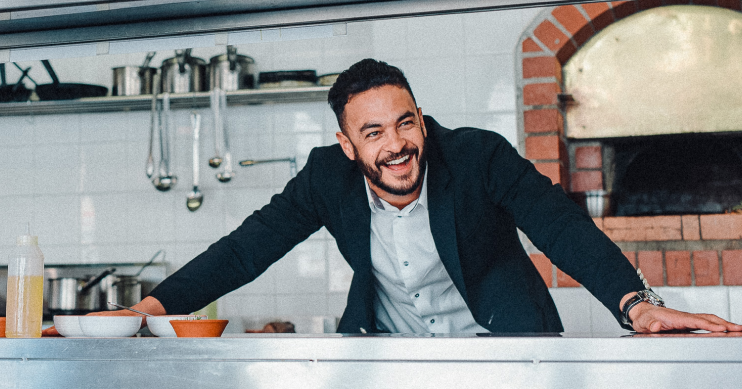 A man smiles behind the counter of a restaurant