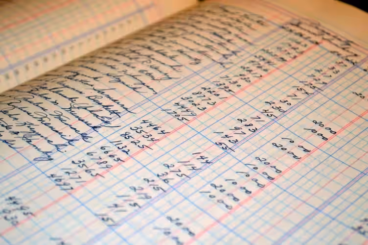 An open ledger book with handwritten financial entries and numbers, symbolizing meticulous bookkeeping for small business success.