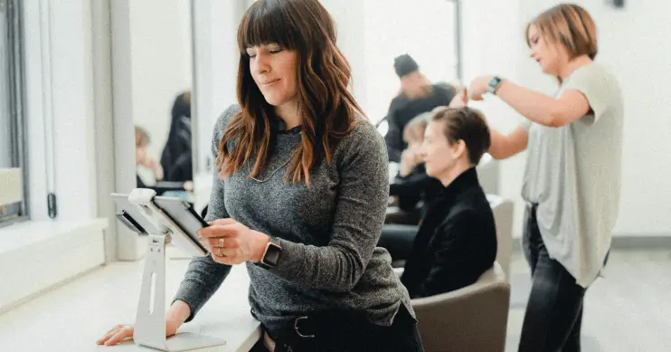 woman in salon looking at iPad on stand