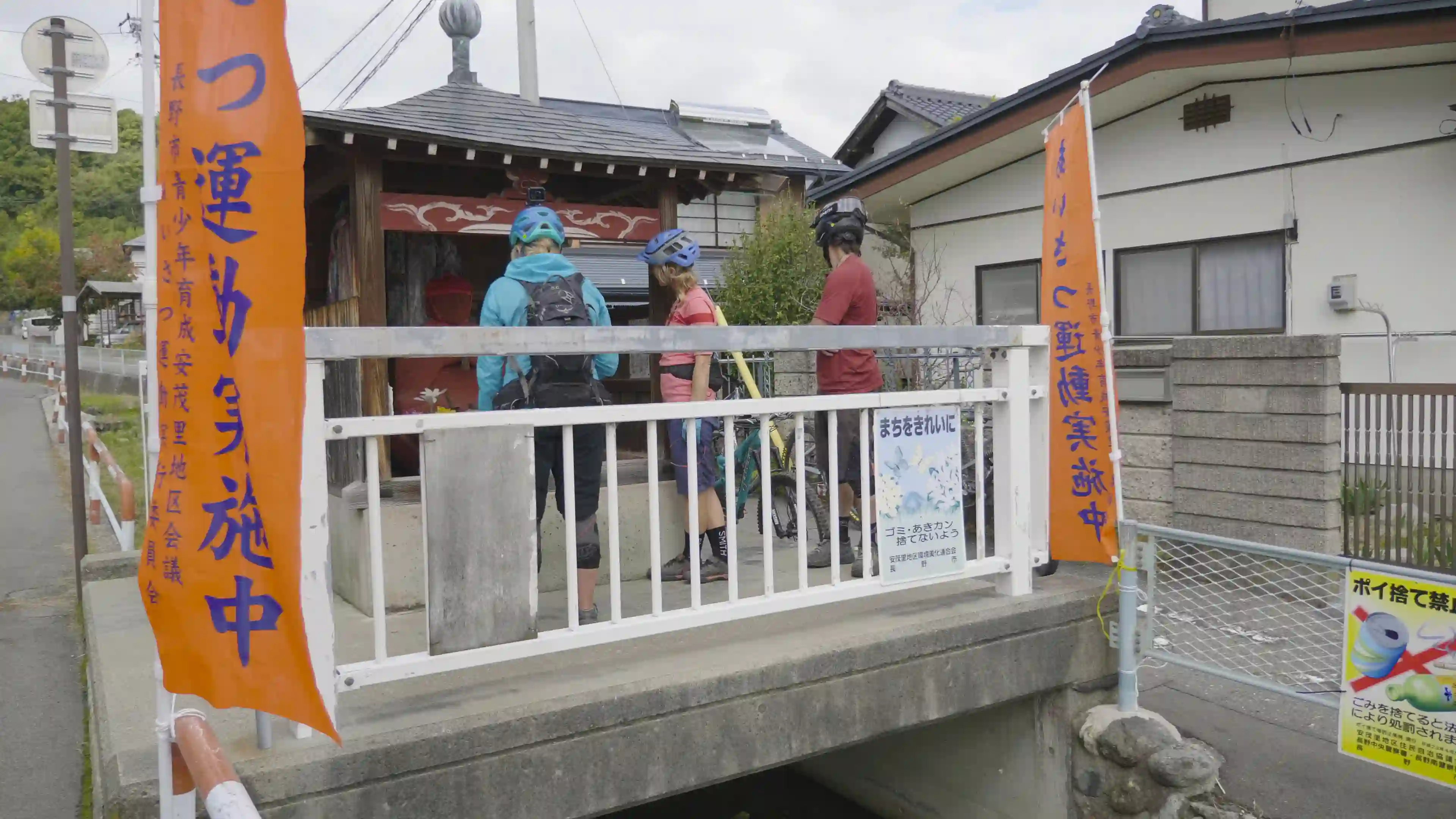 Two mountain bikers stop at a shrine located in a village.