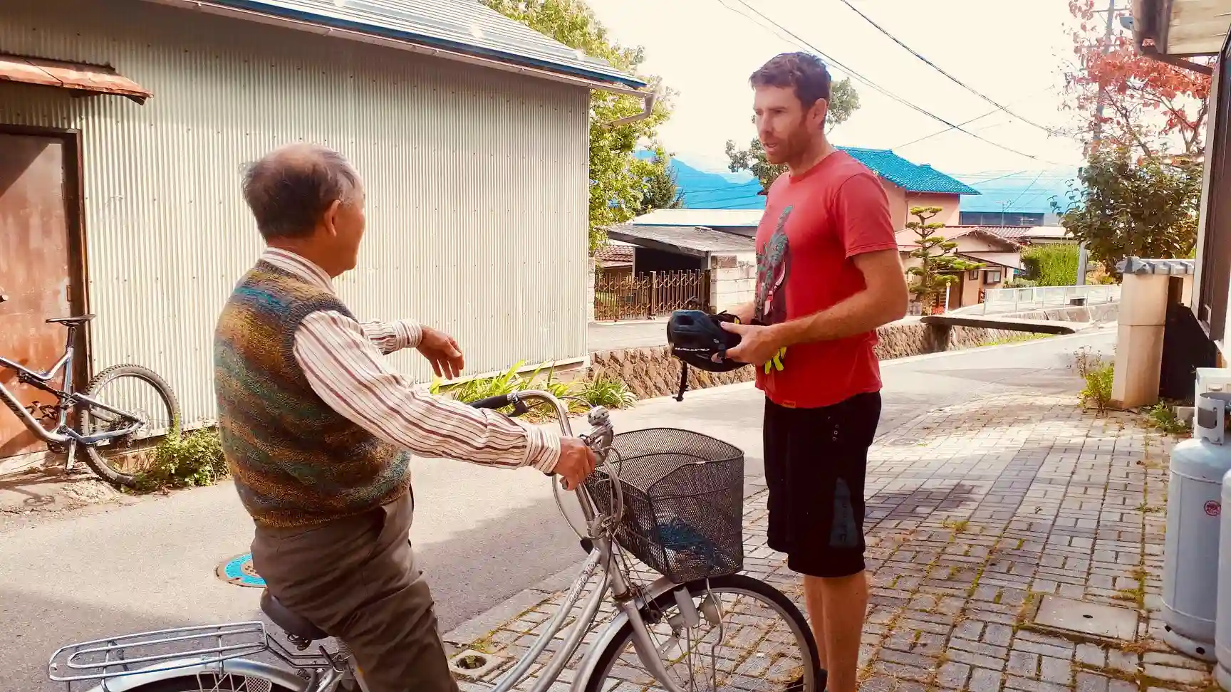 A visiting mountain biker talks to a local on a town bike.