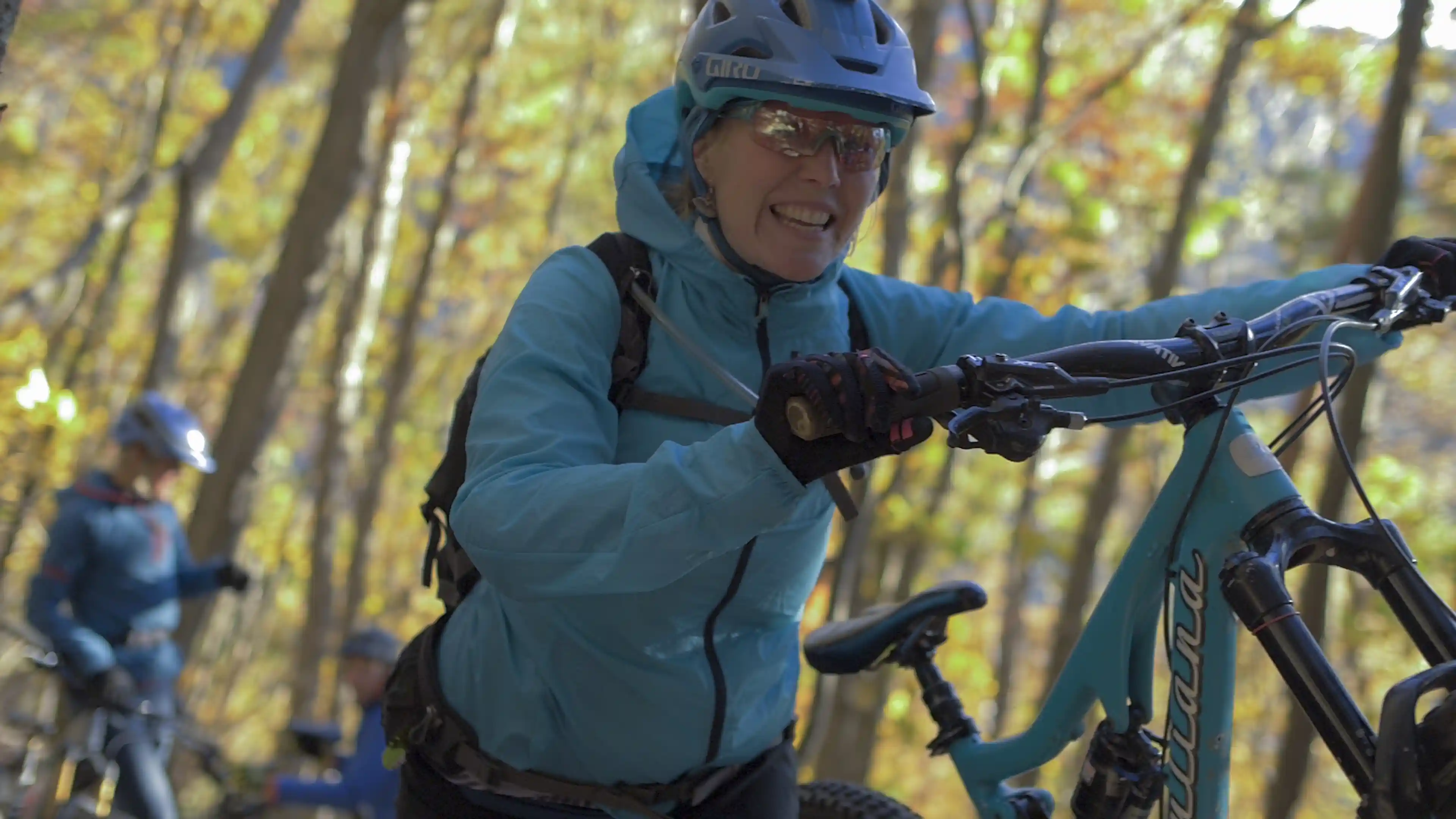 A mountain biker pushes pretty blue bike up a steep section.