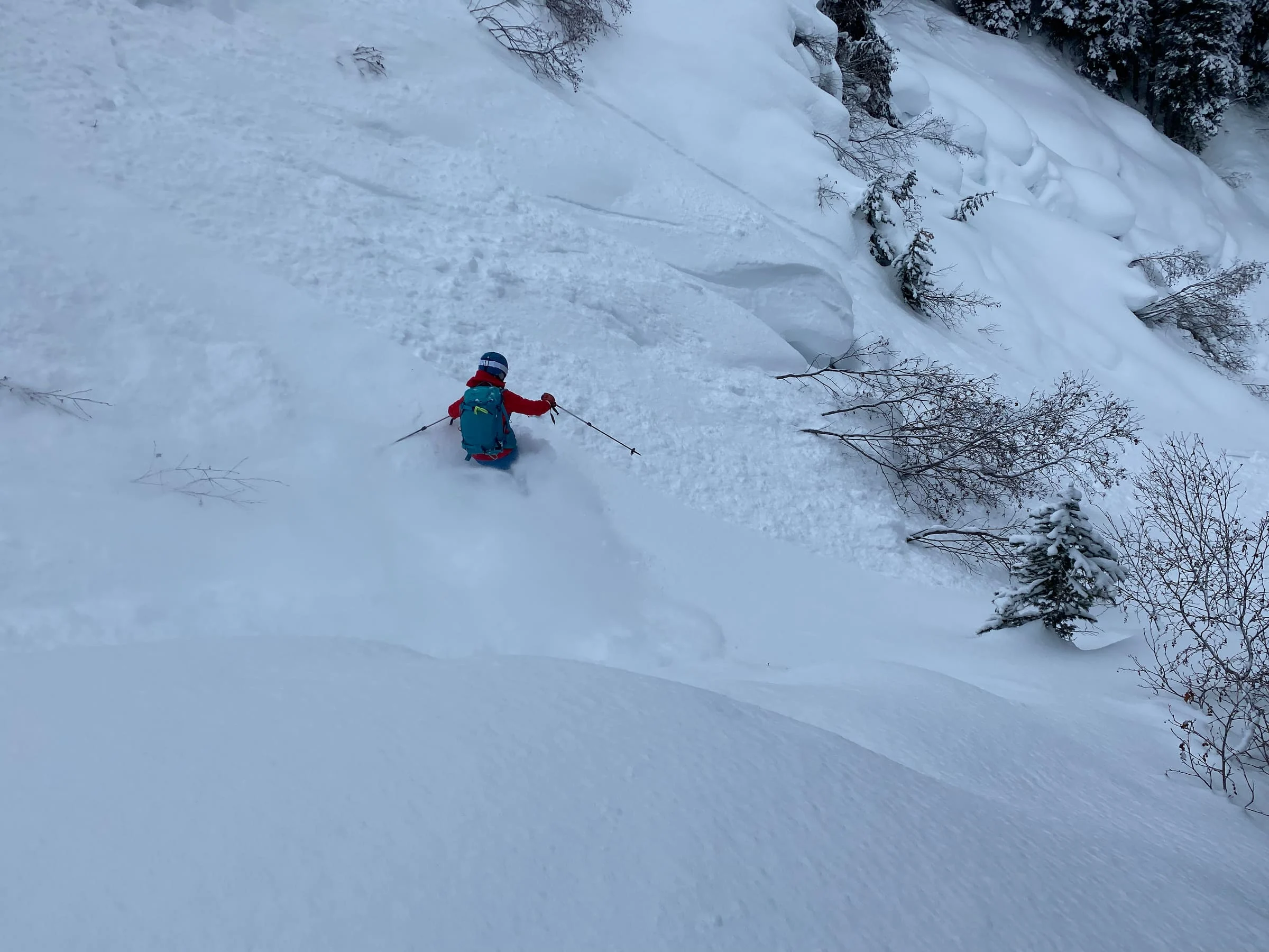 A backcountry skier skis a steep avalanche path 