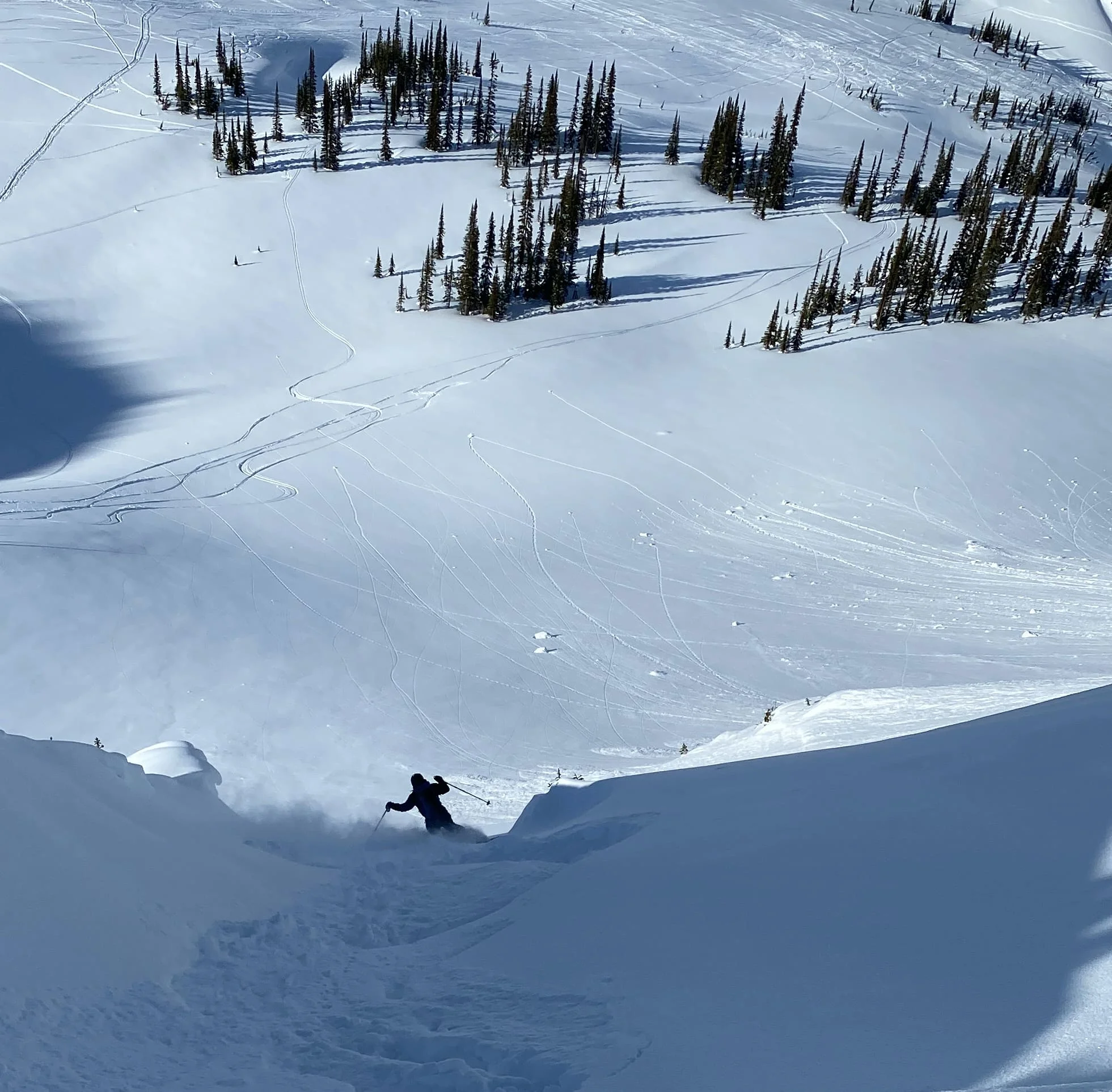 Looking down a very steep shoot feature, skier exiting at the bottom