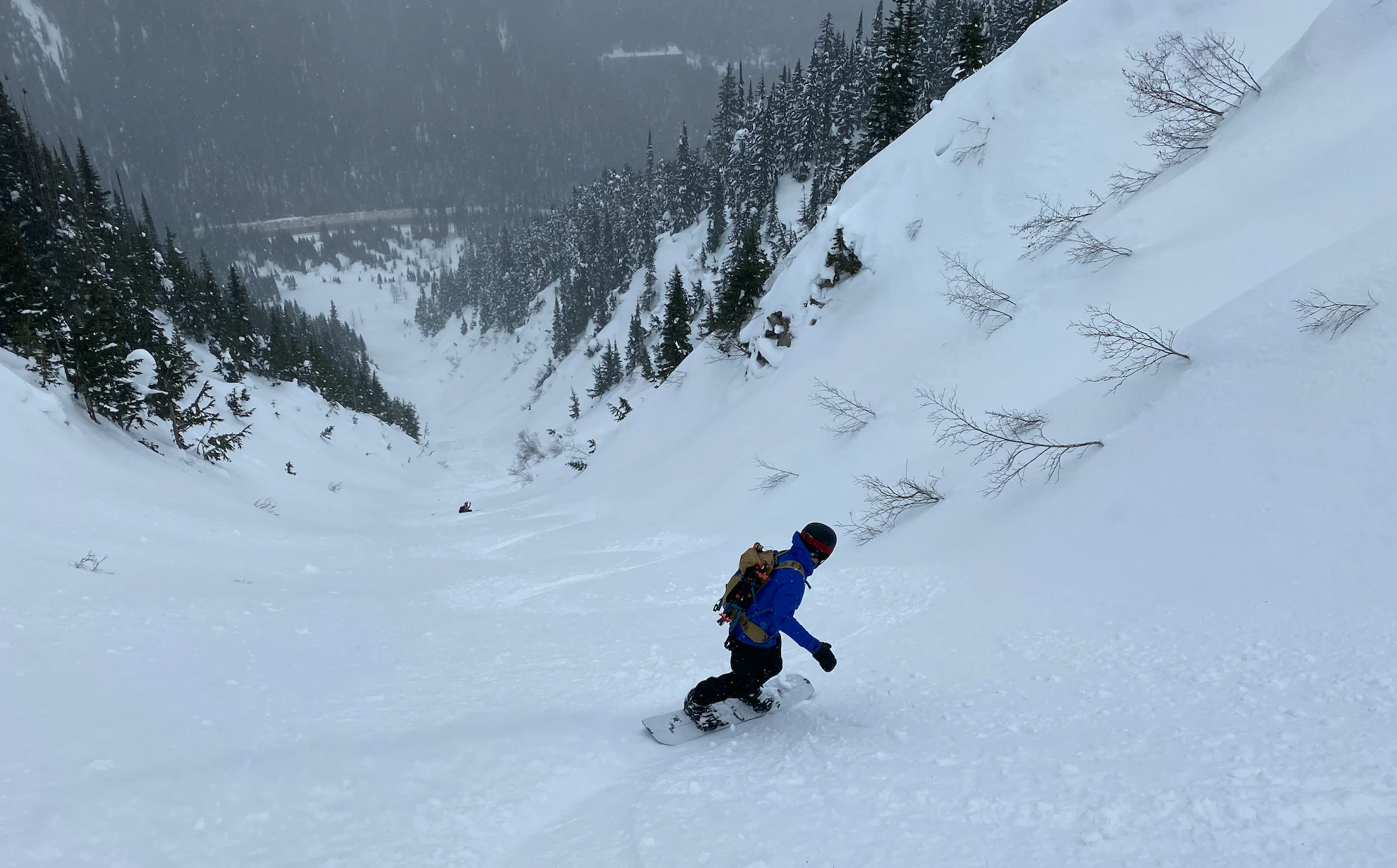 A backcountry snowboarder rides a large gully feature