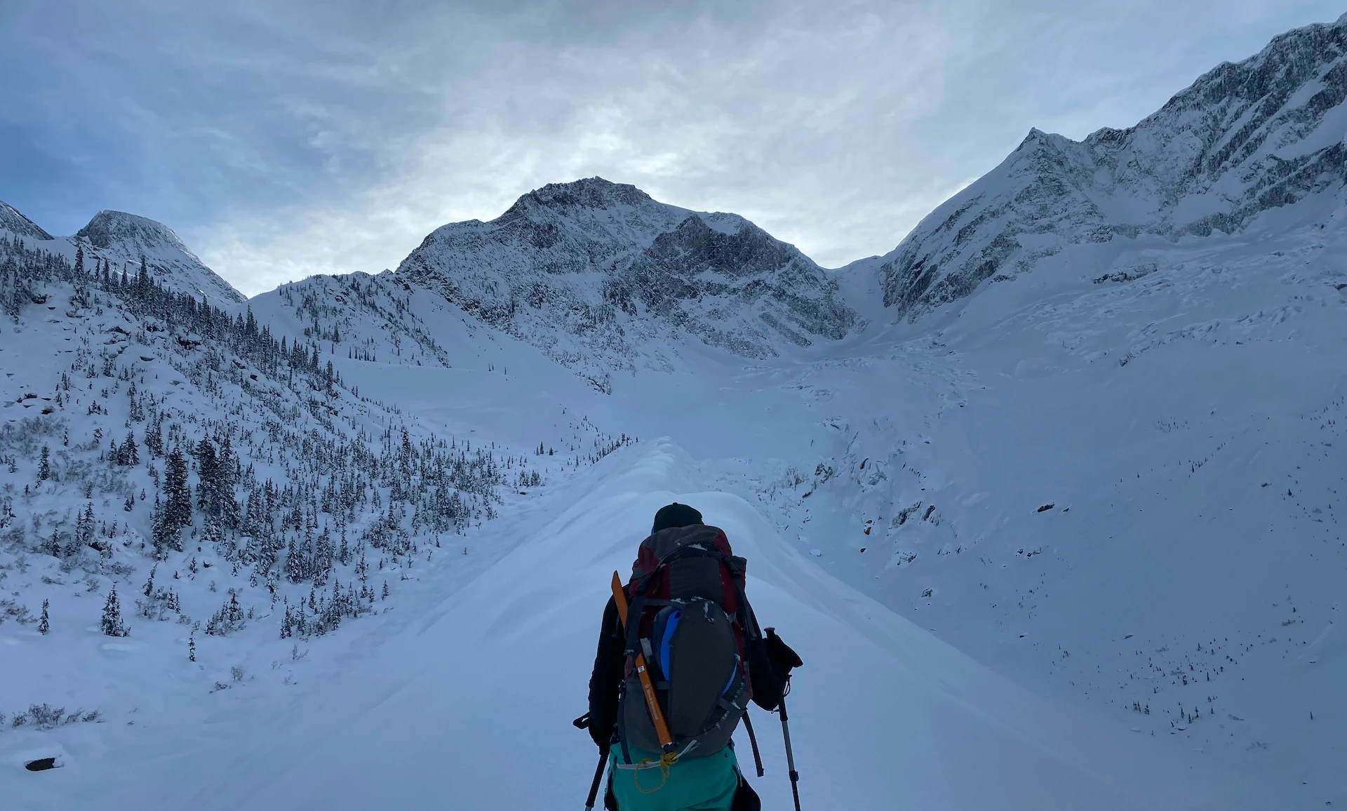 A backcountry skier skins along a moraine ridge