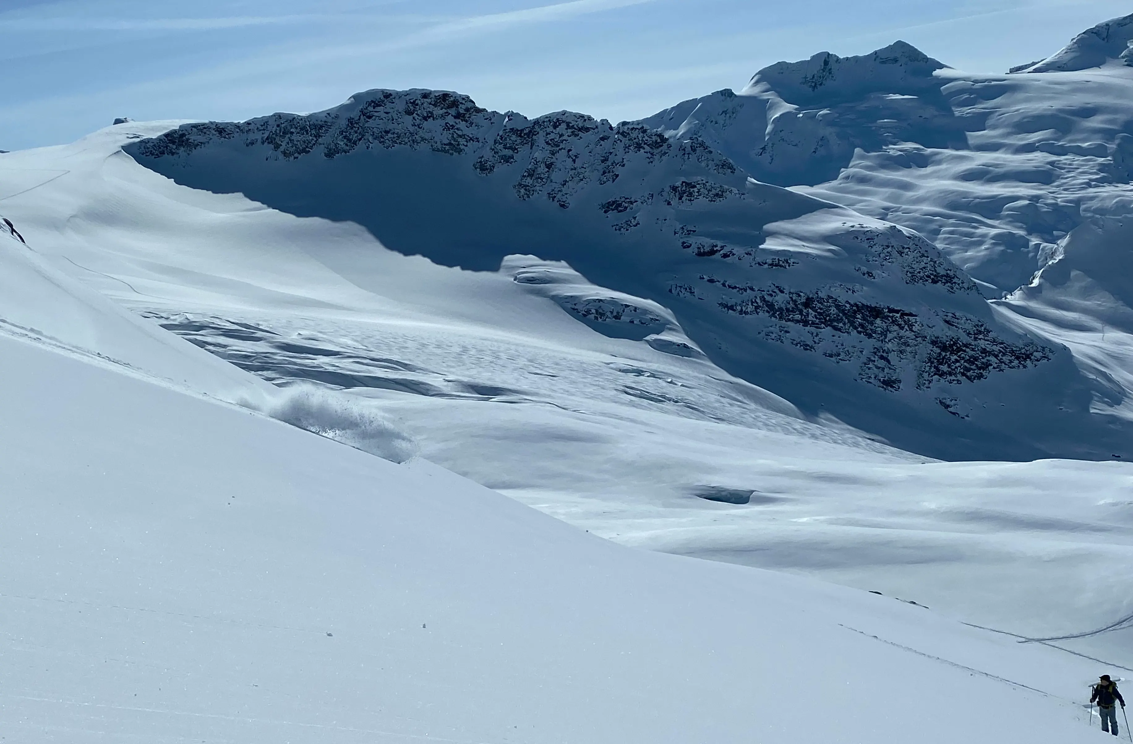 A backcountry snowboarder sprays snow with broken glaciers in the background