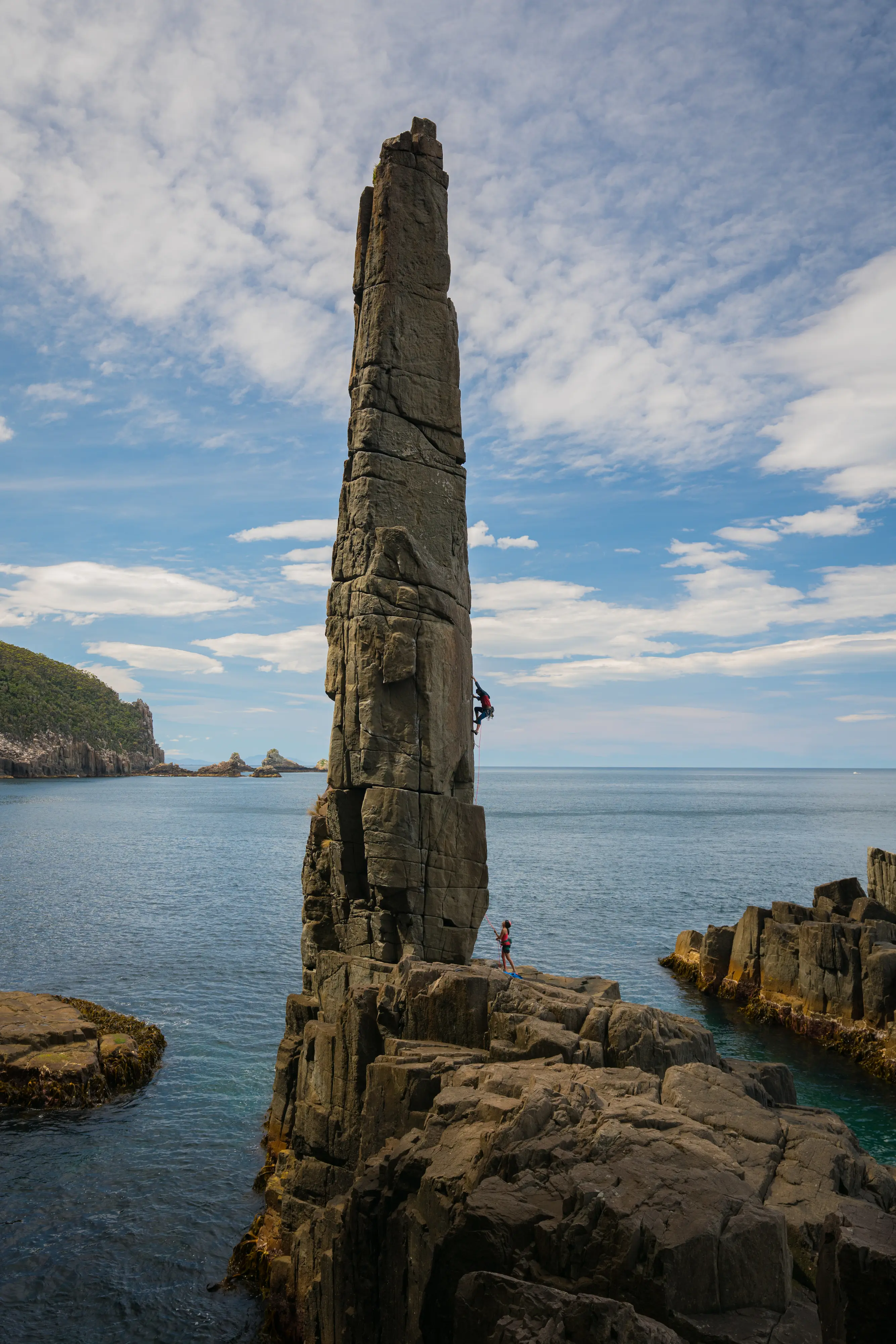 A climber ascends an impressive sea stack, Tasmania