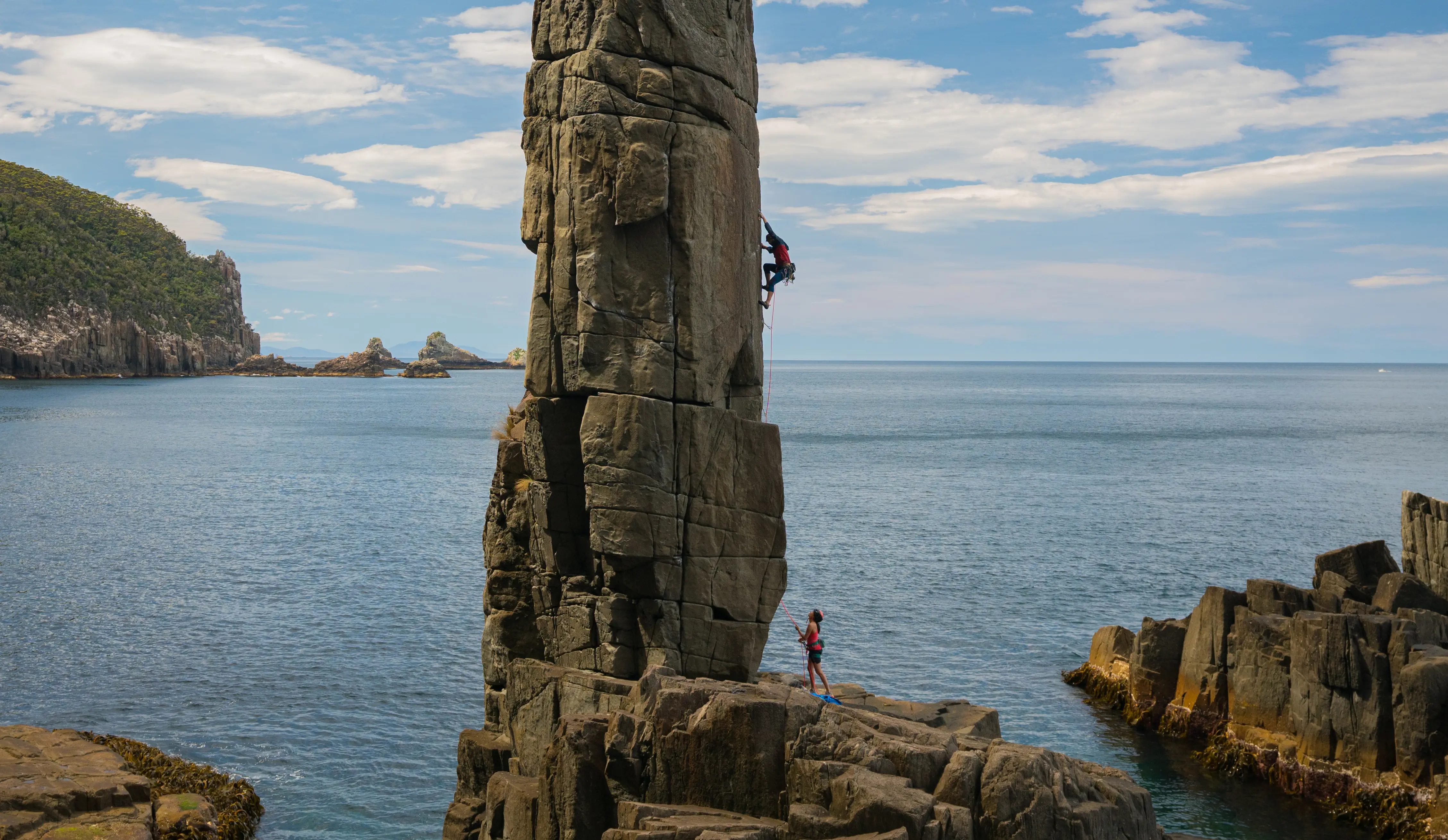 Climber climbing a sea stack, Tasmania
