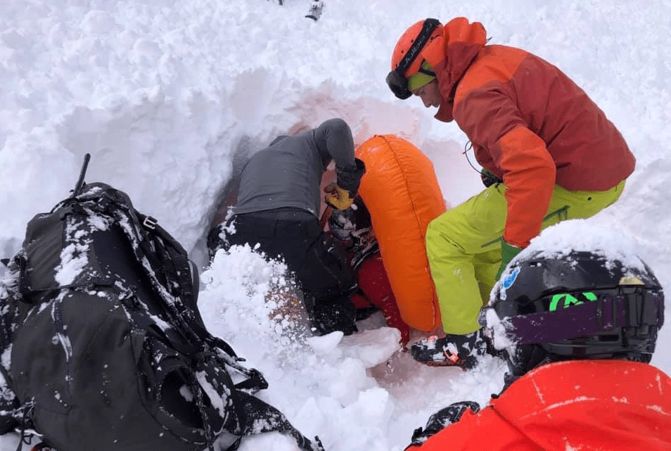 Two people dig out a buried snowboarder,  Hakuba 