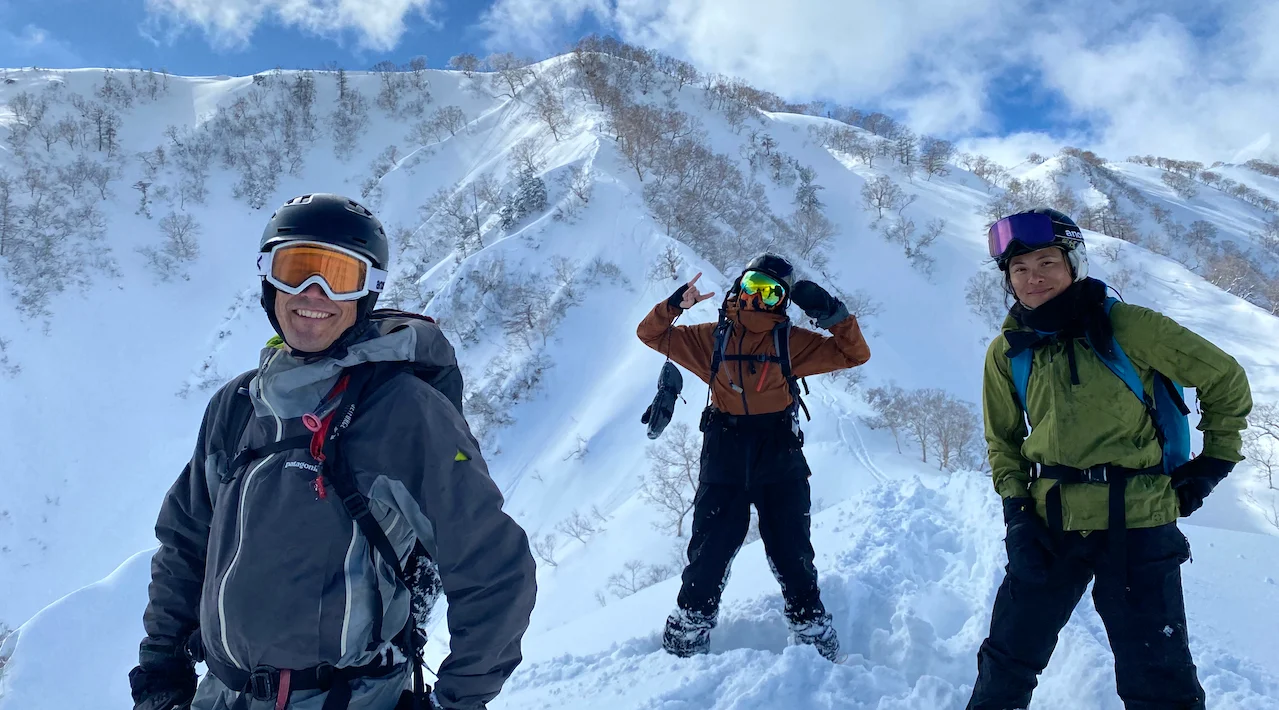 Three backcountry snowboarders with beginner spine behind