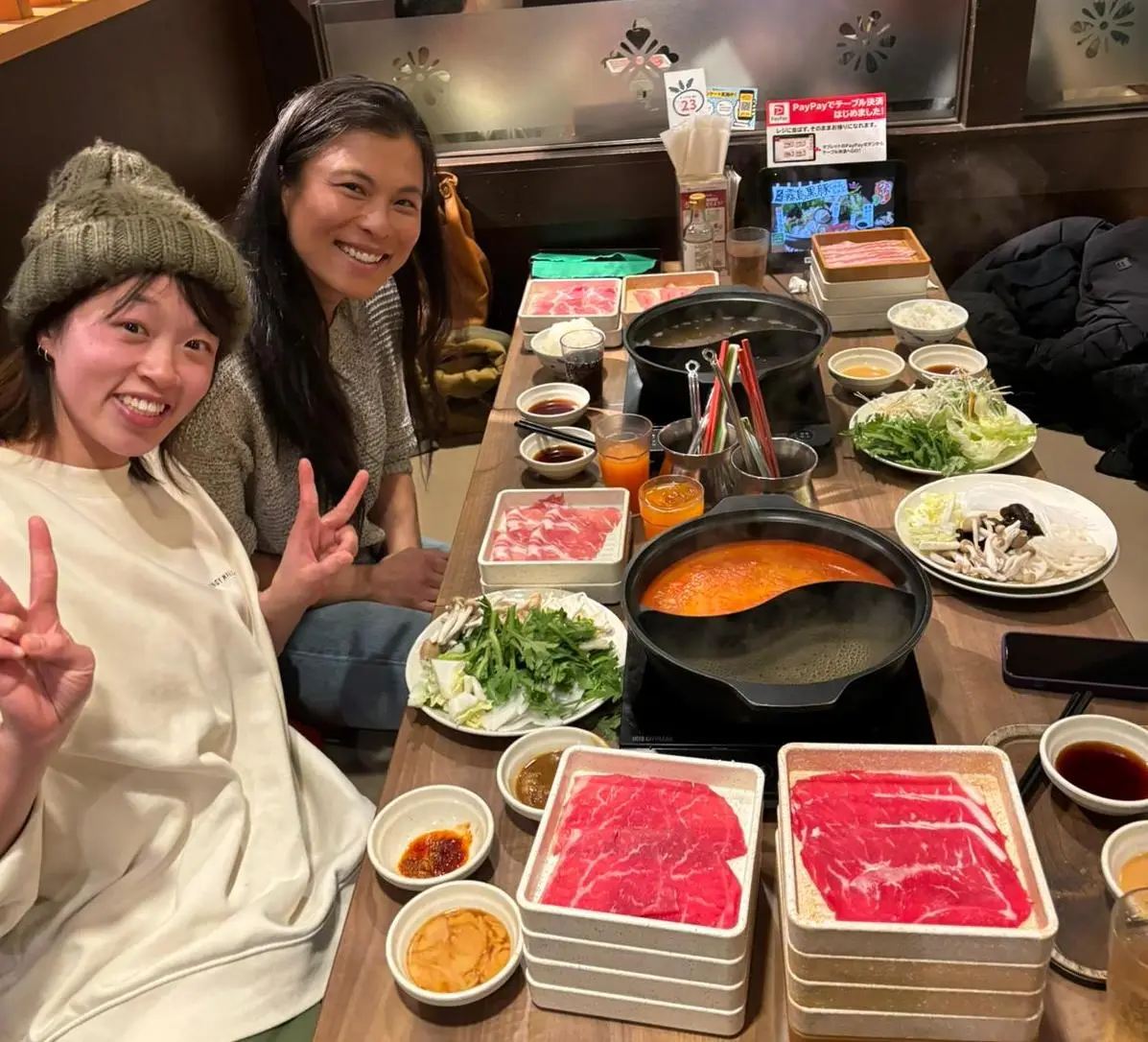 Two women seated at a table with Shabu-shabu meal