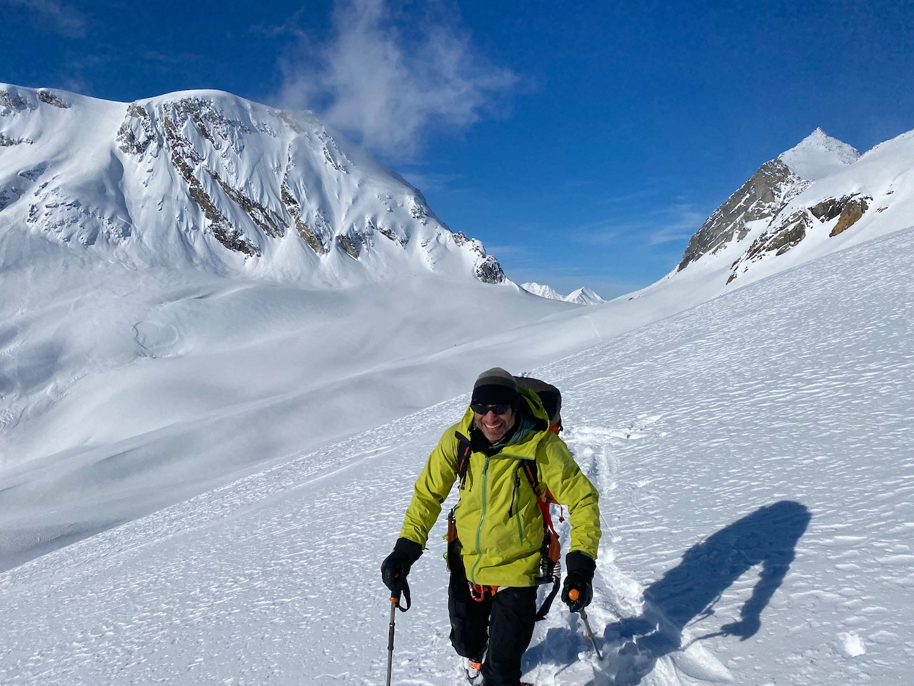 I ski tourer with a big grin and a high mountain pass in the background