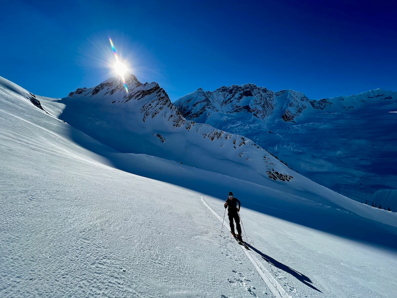 Skinning in the alpine with deep blue mountains in the back