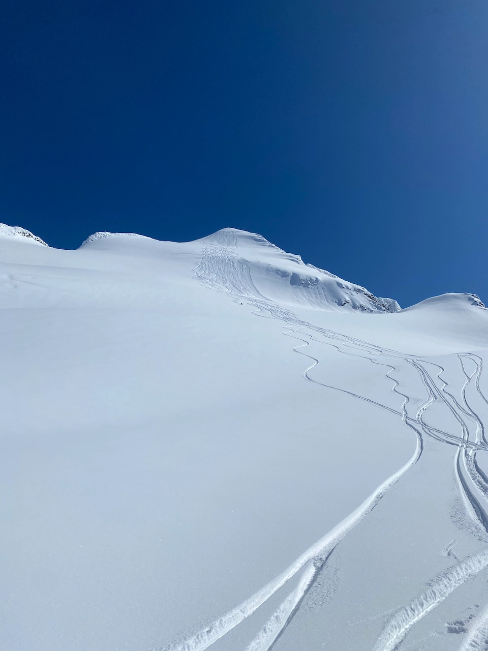 Skier and ski track coming from a high peak