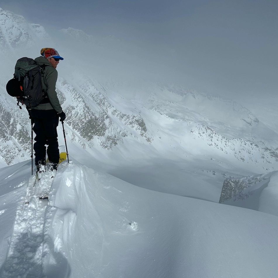 A guide on top of a summit looking down the run