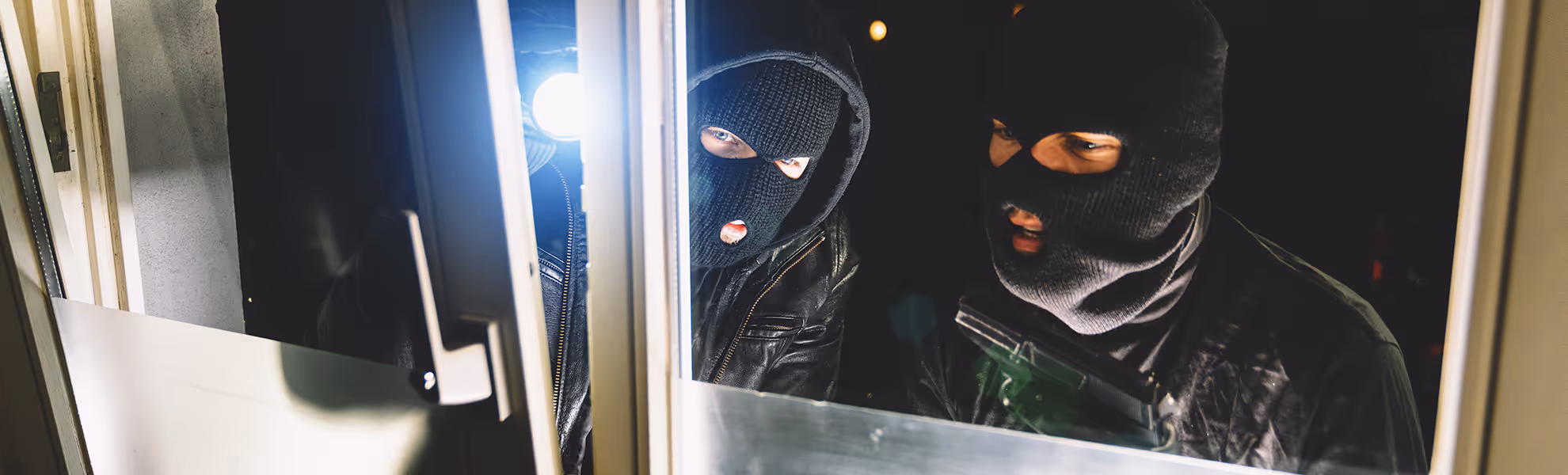 Einbrecher versucht, eine gesicherte Tür mit Werkzeugen zu öffnen – Symbolbild für effektiven Schutz vor Einbrechern durch moderne Sicherheitstechnik