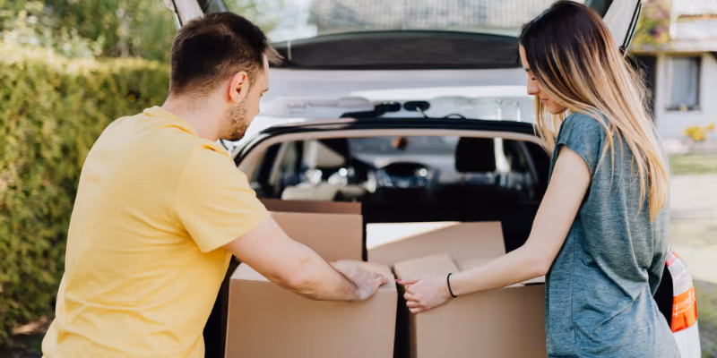 des étudiants qui sortent leurs cartons d'un coffre de voiture