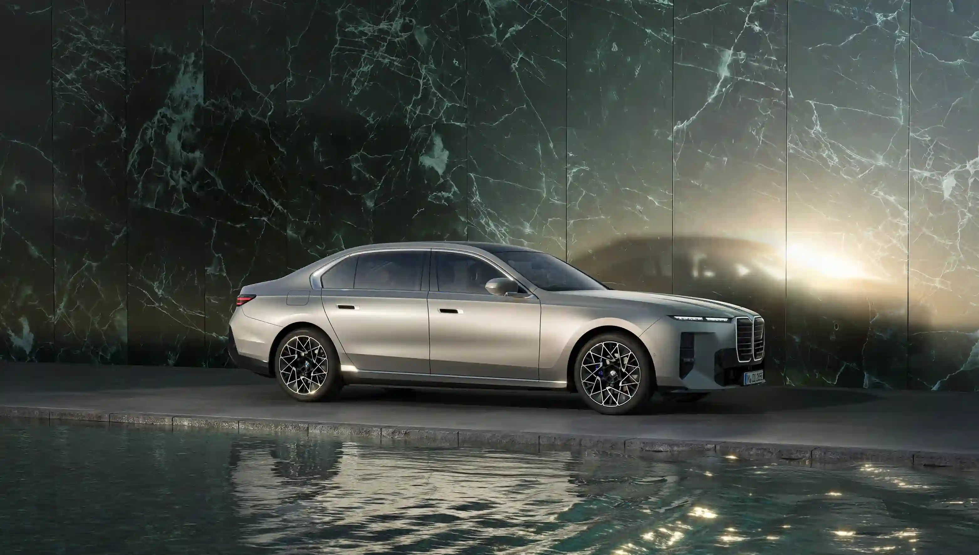 BMW i7 zwischen einer grünen Marmorwand und Wasser.